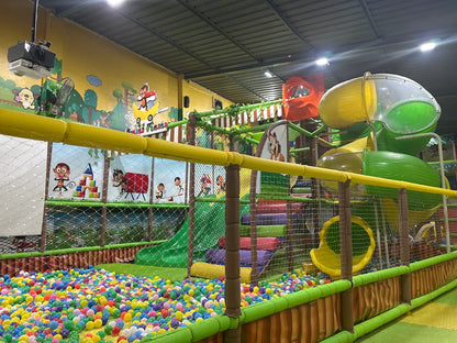 A colorful indoor playground with slides, ball pit, and jungle-themed decorations for children.