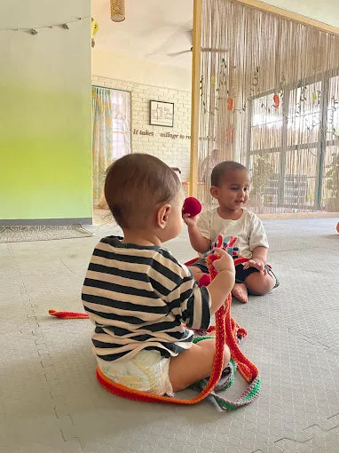 Two children playing with colorful toys on a soft cushioned floor.