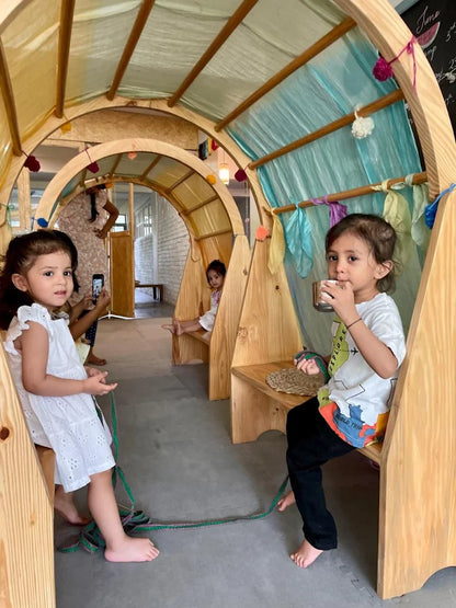 Children playing inside a wooden playhouse with a modern interior.