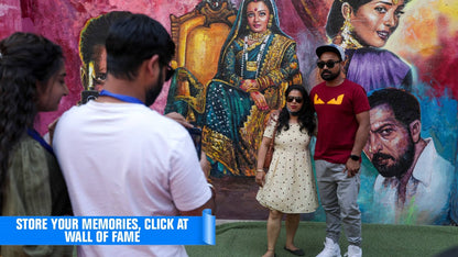 Young adults pose in front of a colorful mural featuring portraits of people.