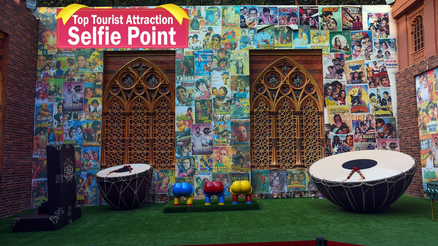A selfie point decorated with vintage Bollywood movie posters, featuring large drums and colorful stools.