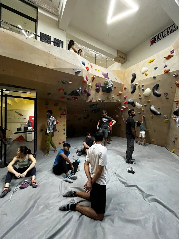 Young adults bouldering and resting in a climbing gym.