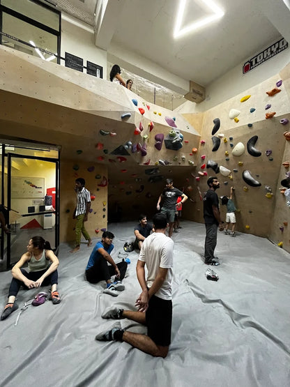 Young adults bouldering and resting in a climbing gym.