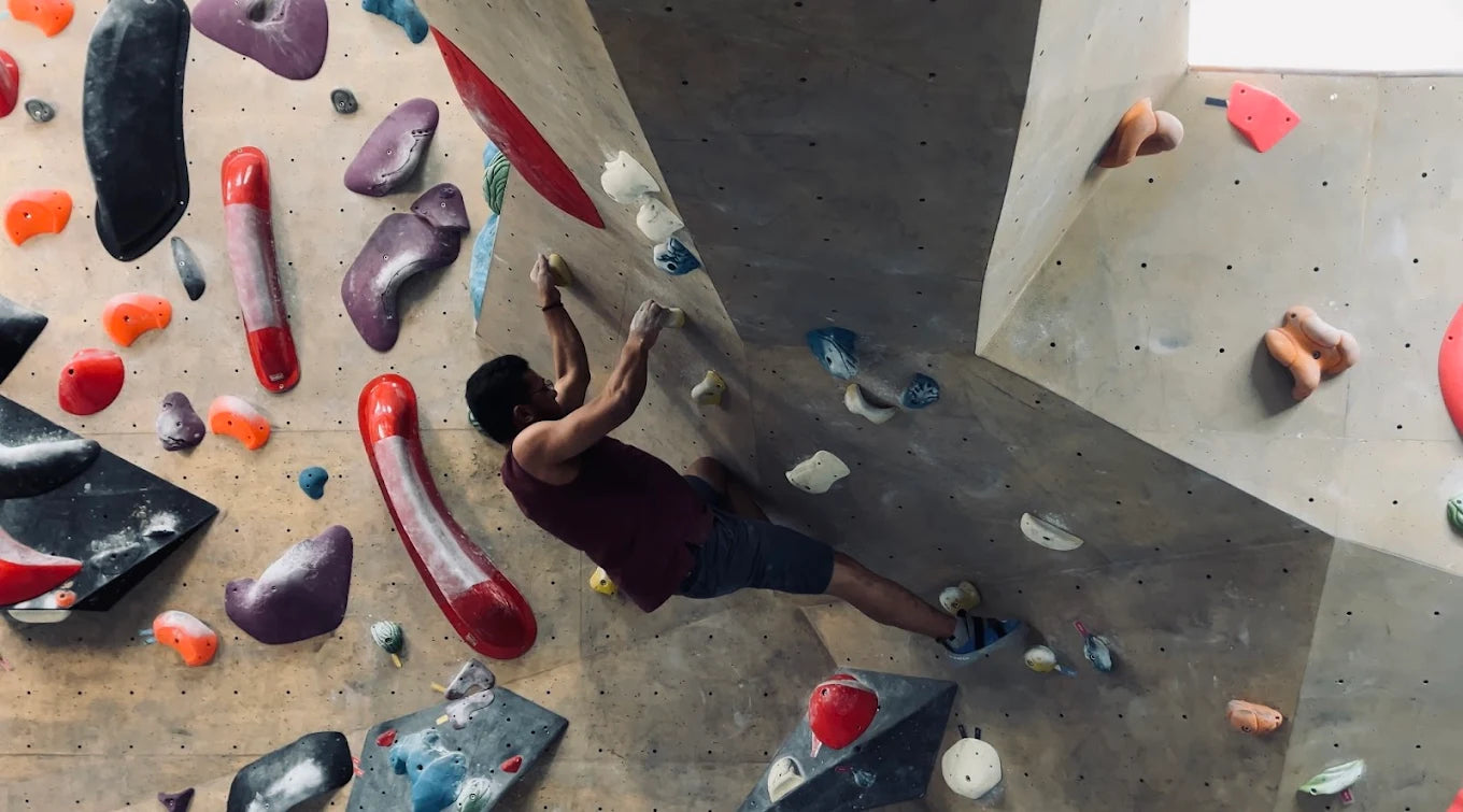 A man climbs a colorful indoor rock climbing wall.