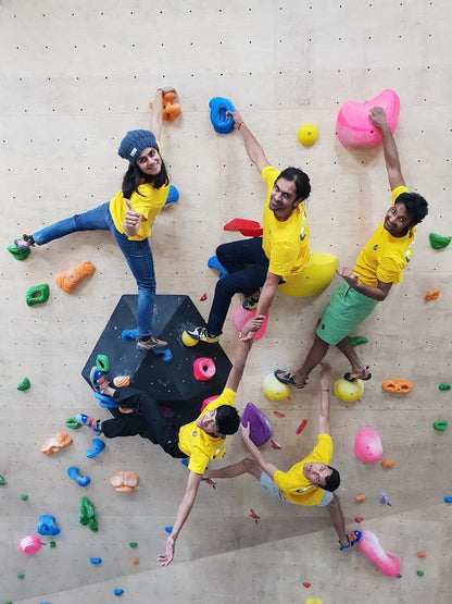 Young adults climbing a colorful indoor rock wall.