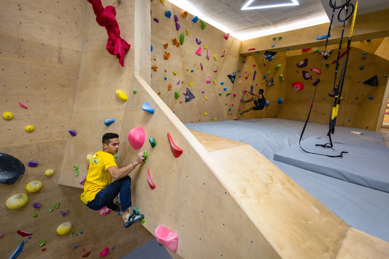 Young men climbing on a colorful indoor bouldering wall.