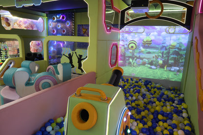 A colorful indoor playground with a ball pit and interactive projection screen for children.