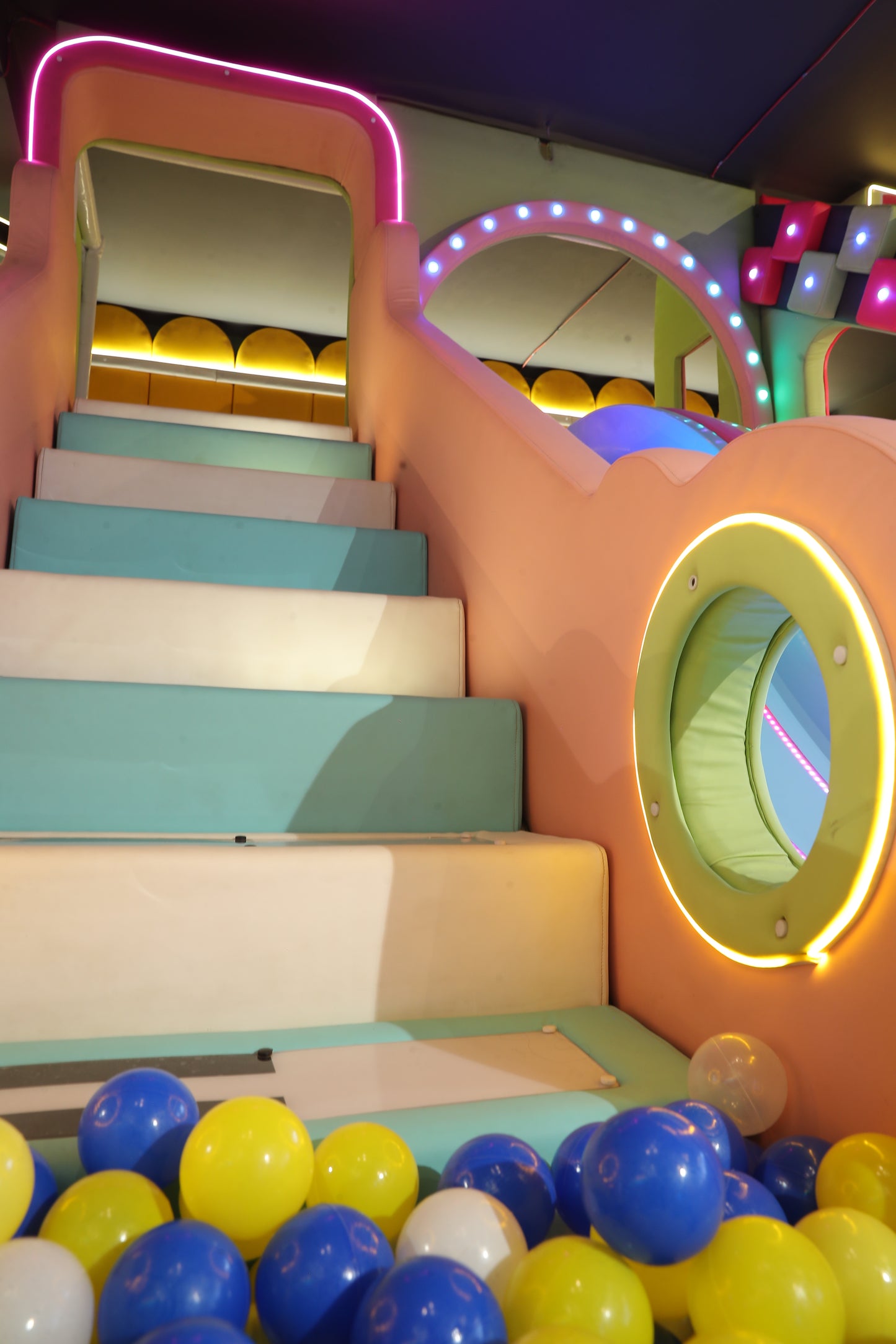 A colorful ball pit with a slide and soft steps, suitable for young children.