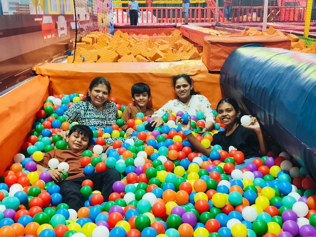 A family enjoys a ball pit at an indoor playground.