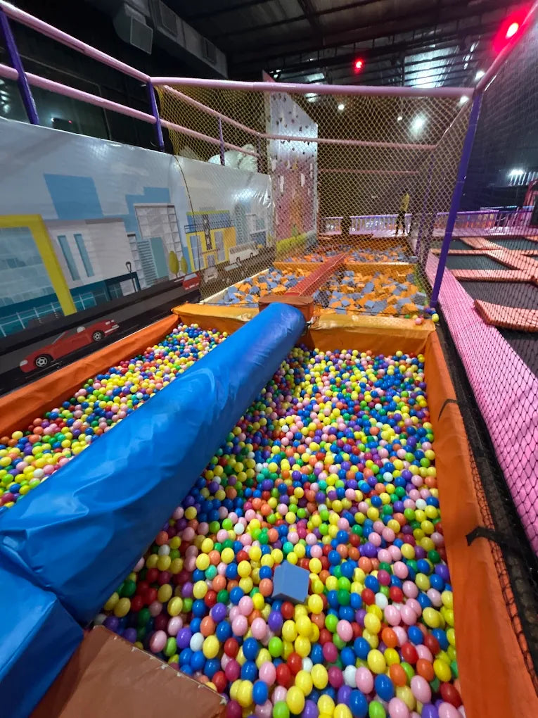 A ball pit filled with colorful balls and a blue slide in an indoor play area.