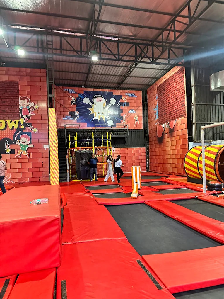 An indoor trampoline park with children and adults jumping.