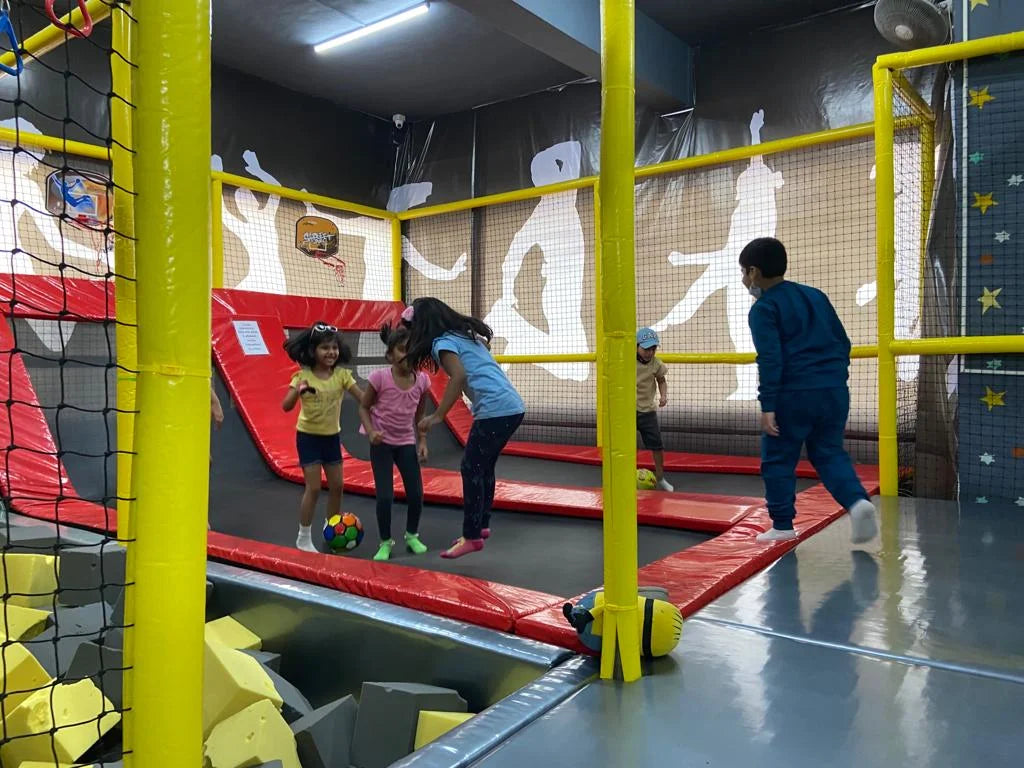 Children play on trampolines in an indoor play area.