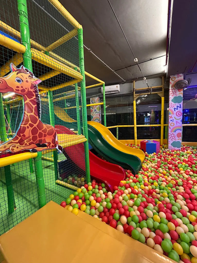 A colorful ball pit with slides and a giraffe cutout in a children's play area.