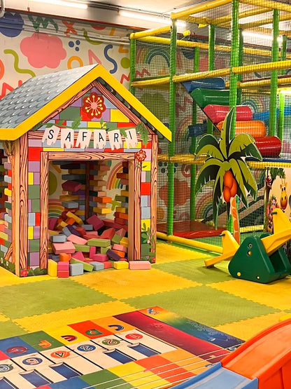 A colorful indoor playground with a "Safari" themed playhouse, soft blocks, and a large climbing structure.