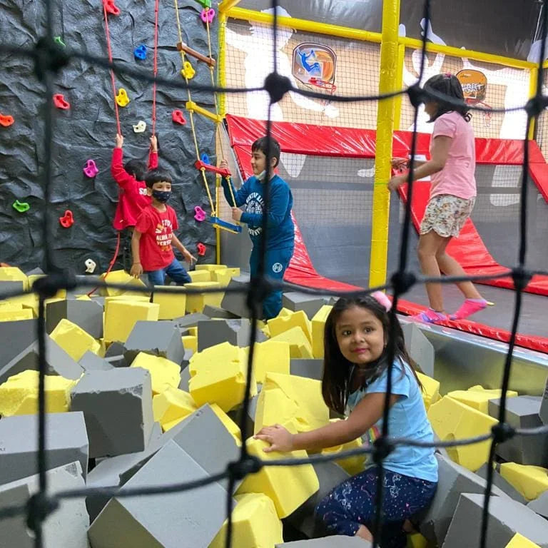 Children play in a foam pit at an indoor trampoline park.