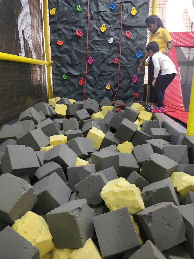 A child and adult at a climbing wall with a foam pit.