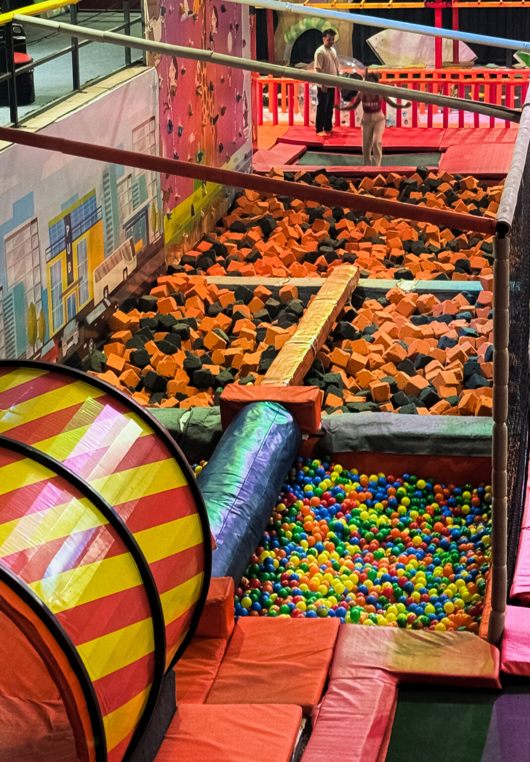 A foam pit and ball pit at an indoor trampoline park with children playing.