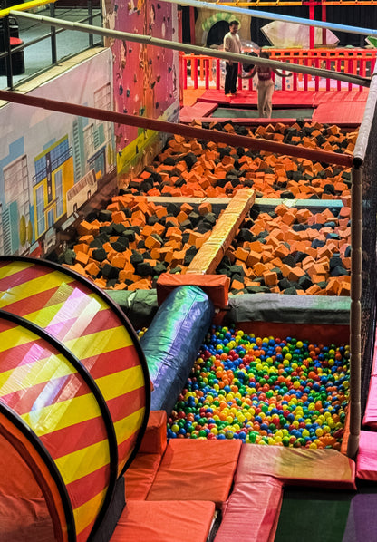A foam pit and ball pit at an indoor trampoline park with children playing.