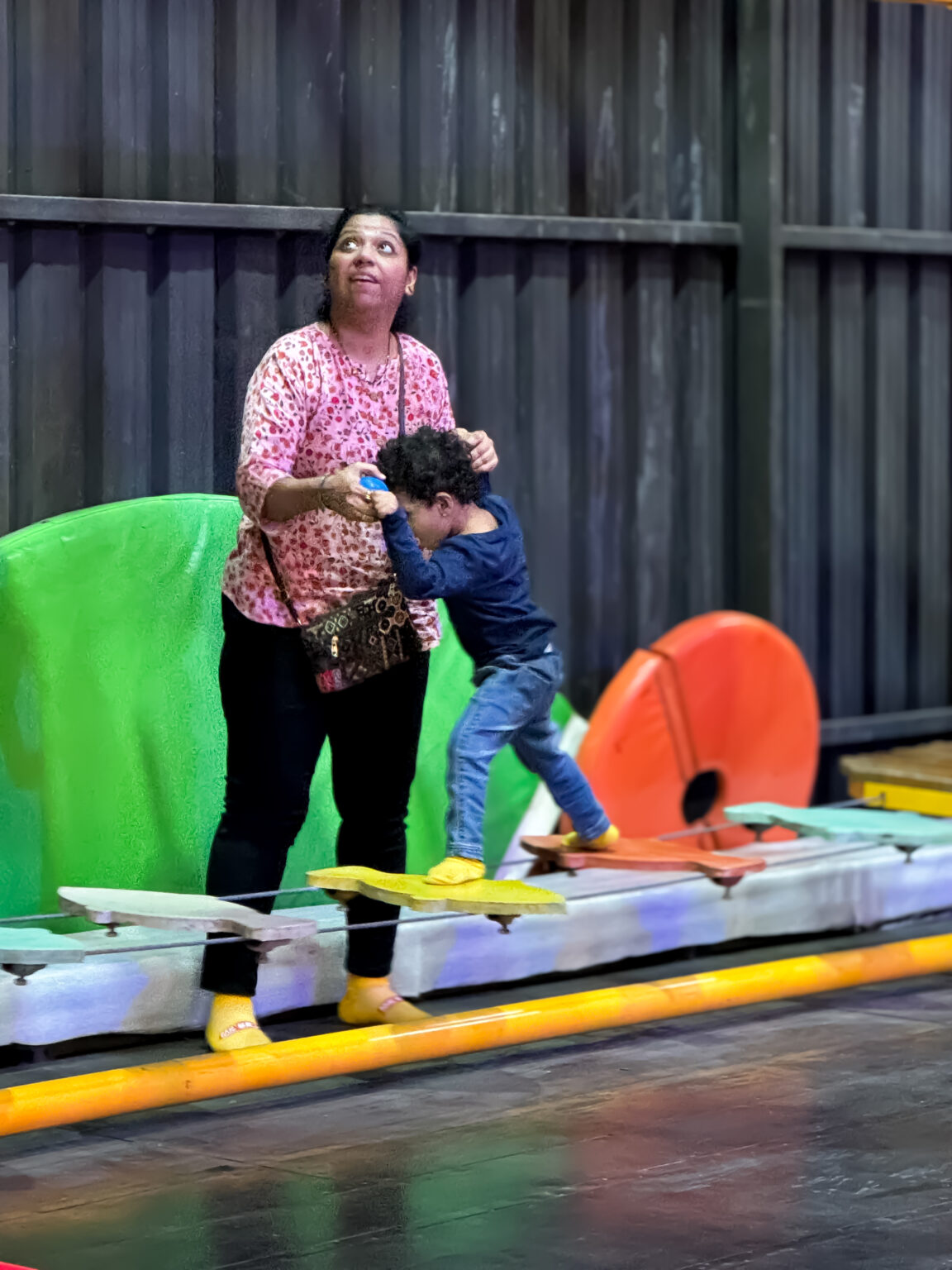 A woman and a young child balance on a wobbly obstacle course.