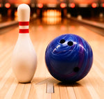Blue bowling ball and white bowling pin on a wooden lane