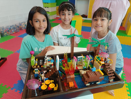 Three children with a large LEGO set on a colorful floor.
