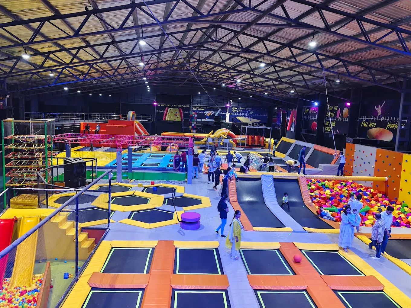 An indoor trampoline park with various attractions and people of all ages enjoying themselves.