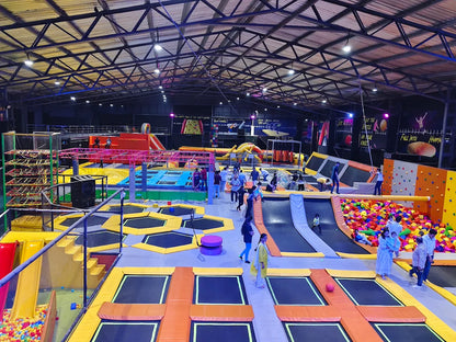An indoor trampoline park with various attractions and people of all ages enjoying themselves.