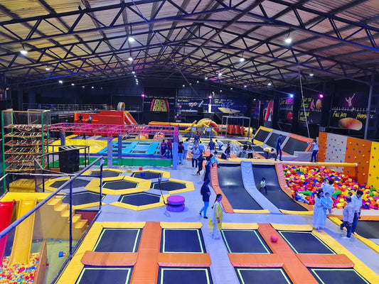 An indoor trampoline park with various attractions and people of all ages enjoying themselves.