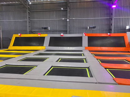 An indoor trampoline park with multiple interconnected trampolines and colorful padding.