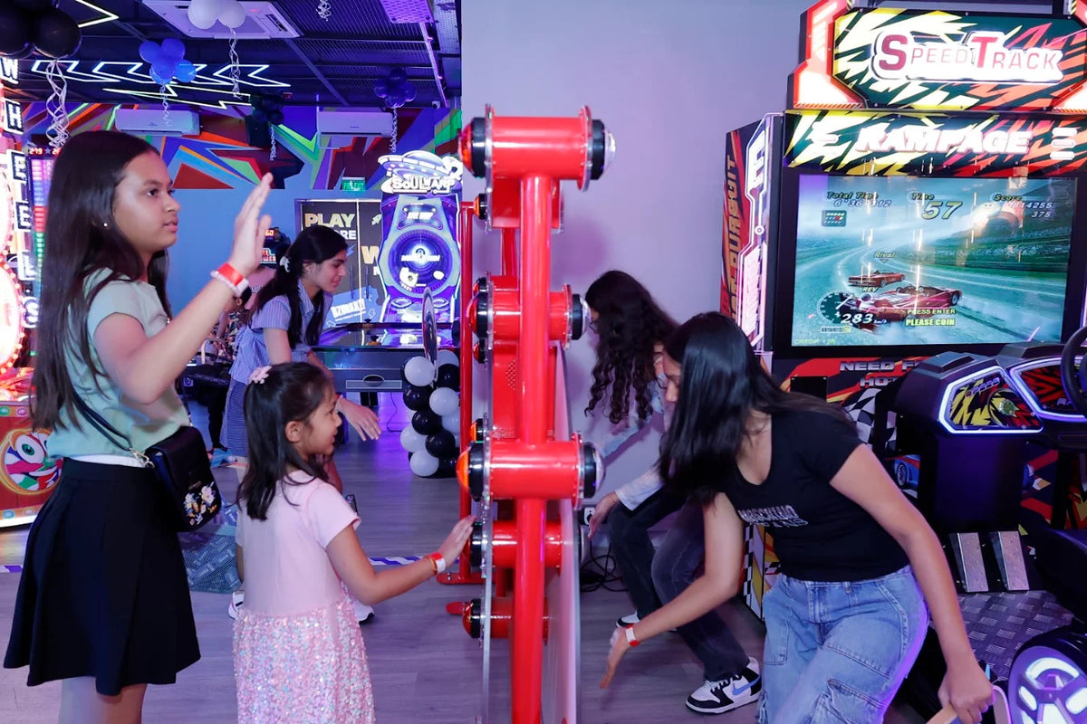 Young people play arcade games in a brightly lit entertainment center.