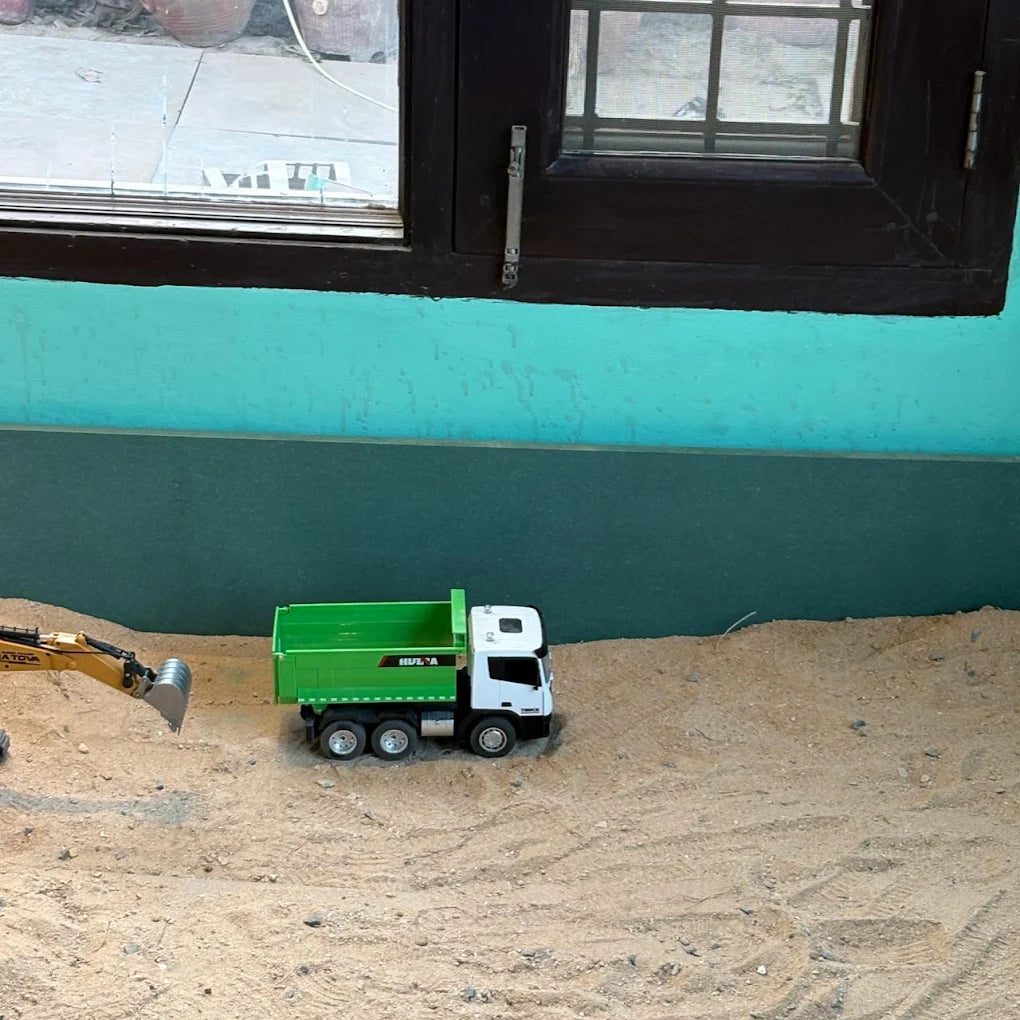 Toy dump truck and excavator in a sandbox.