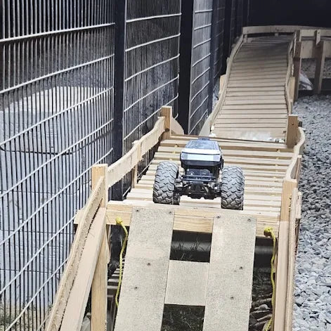 A remote-controlled monster truck is on a wooden ramp.