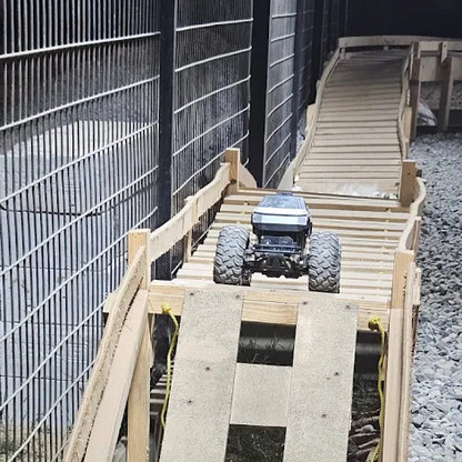 A remote-controlled monster truck is on a wooden ramp.