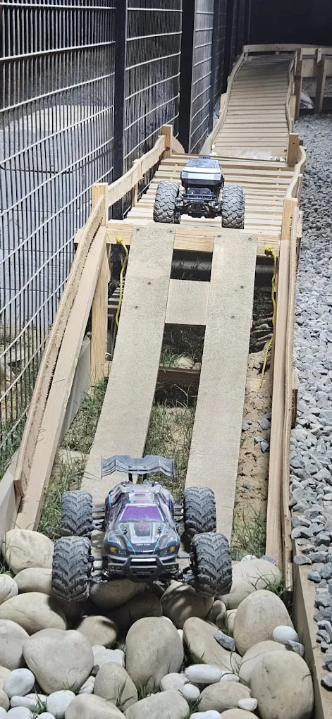 Two remote-controlled monster trucks on a wooden ramp obstacle course.