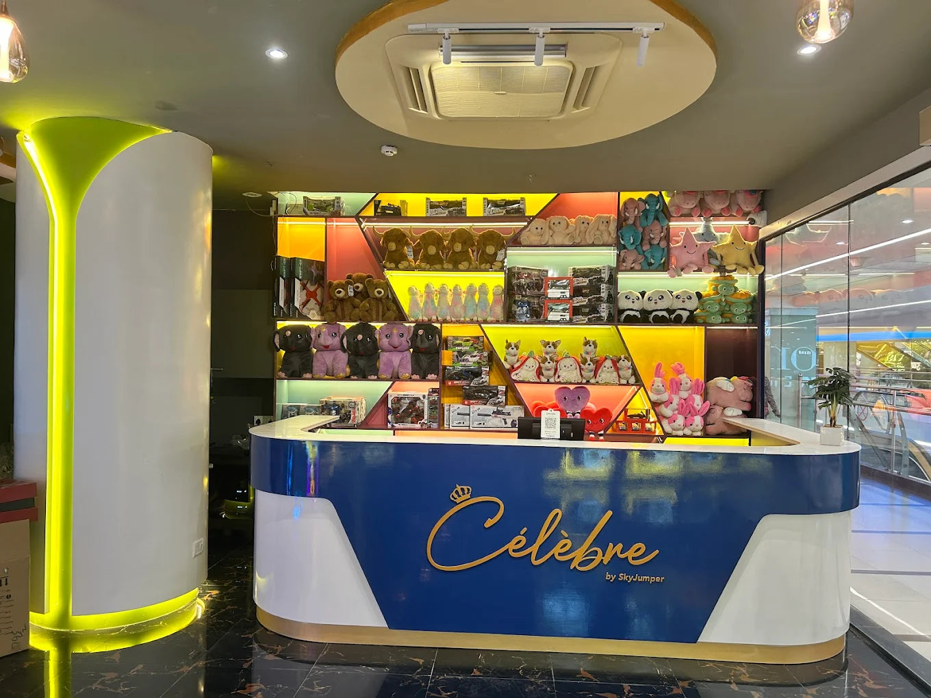 A brightly lit reception desk in a toy store, stocked with stuffed animals and toys.