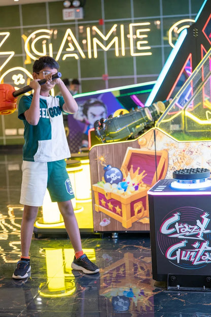 A young boy plays an arcade game with a hammer, surrounded by neon lights and game machines.