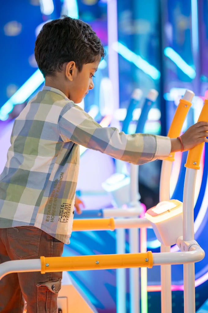 A young boy in a plaid shirt uses an exercise machine in a brightly lit arcade.