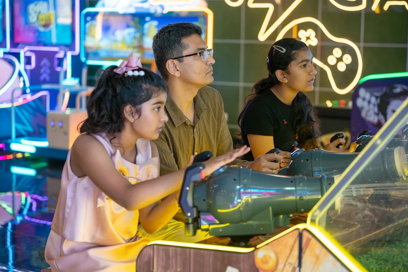 A father and his two daughters play an arcade game together.