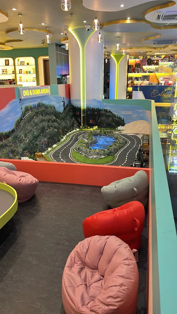 A colorful indoor play area with beanbag chairs and a miniature road and mountain landscape.