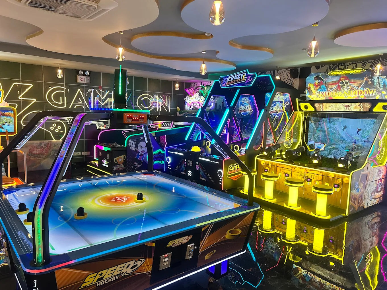 An arcade with neon lights, featuring air hockey and video games.