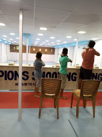 Three young people practice shooting at targets in an indoor range.