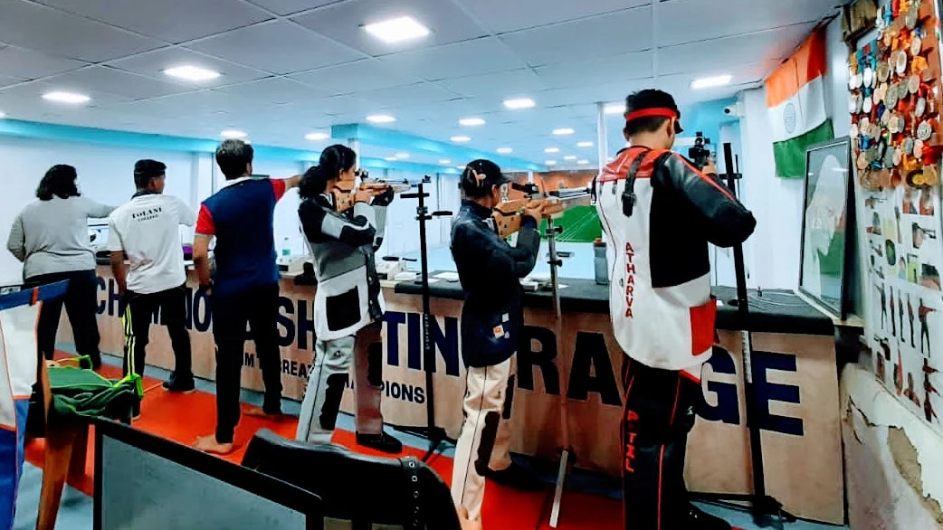 Young athletes practice shooting at an indoor range, aiming at targets.