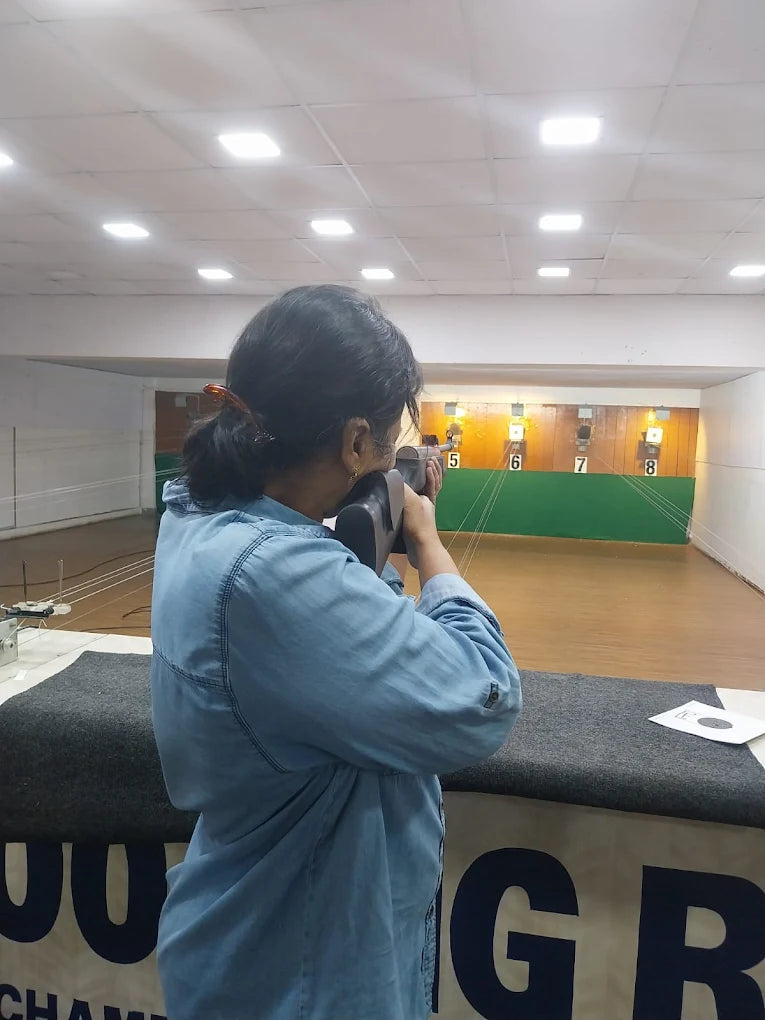 A person aims a rifle at targets in an indoor shooting range.