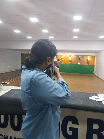 A person aims a rifle at targets in an indoor shooting range.