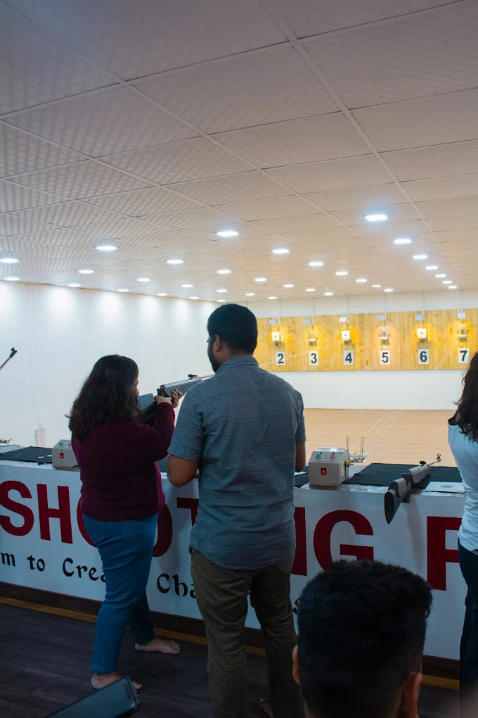 Adults practice shooting at targets in an indoor range.