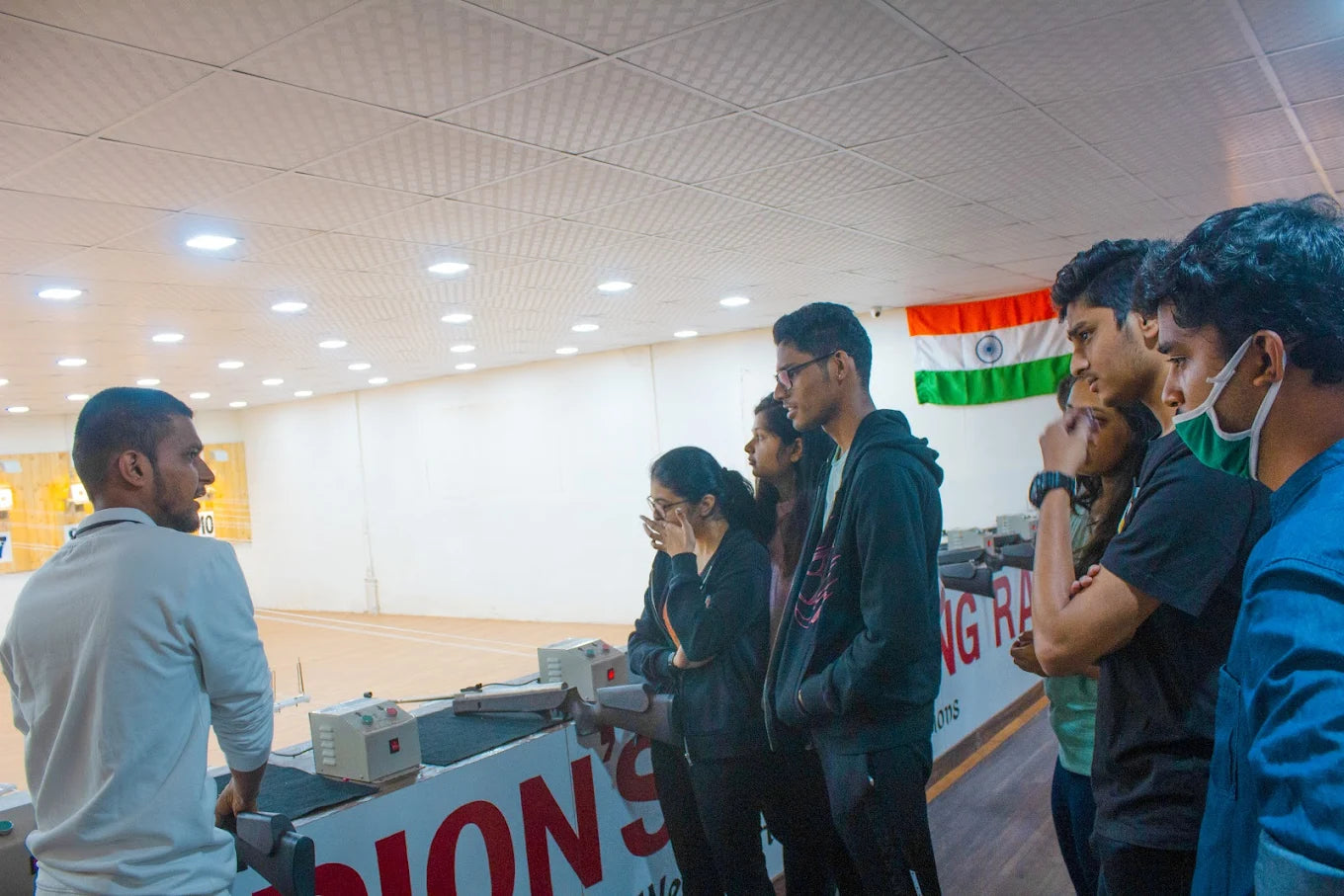 Young adults observe a shooting range with an instructor.
