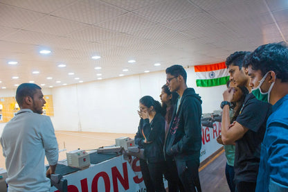 Young adults observe a shooting range with an instructor.