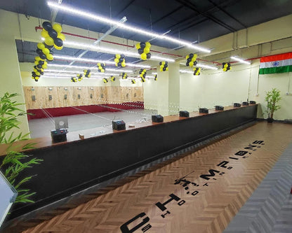 An indoor shooting range decorated with balloons, featuring targets and a wooden floor with a logo.