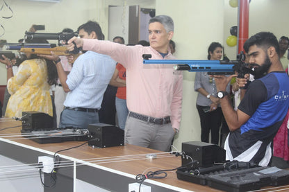 Adults practice shooting with air rifles at a range.