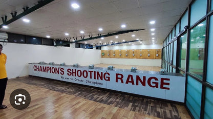 An indoor shooting range with targets and a sign that reads "Champion's Shooting Range."